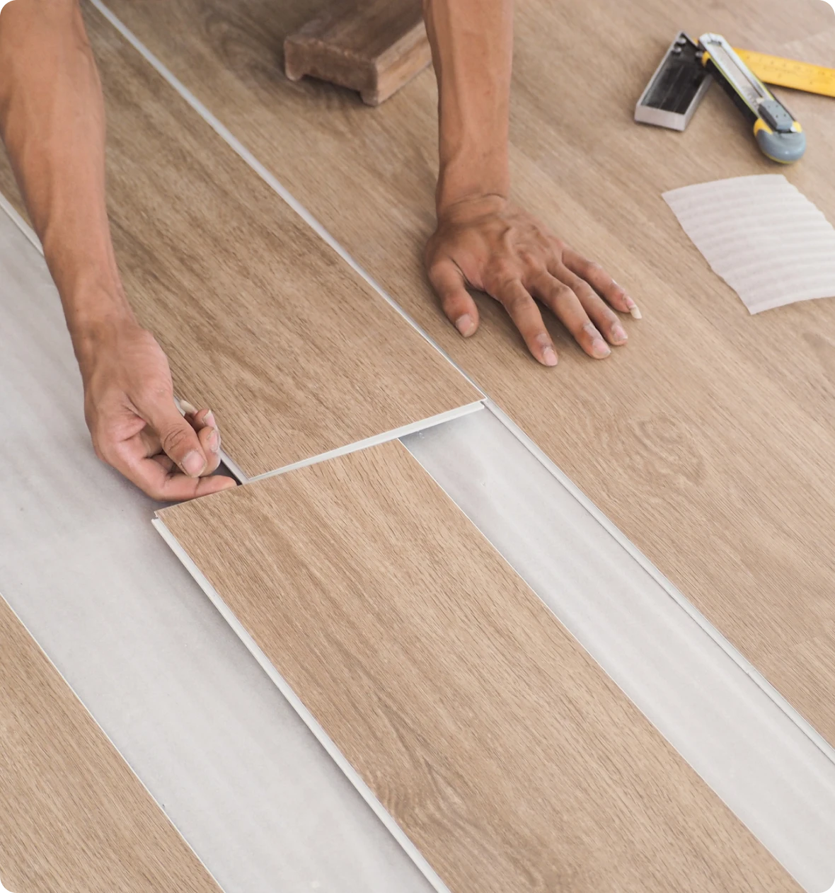 Hands laying laminate flooring