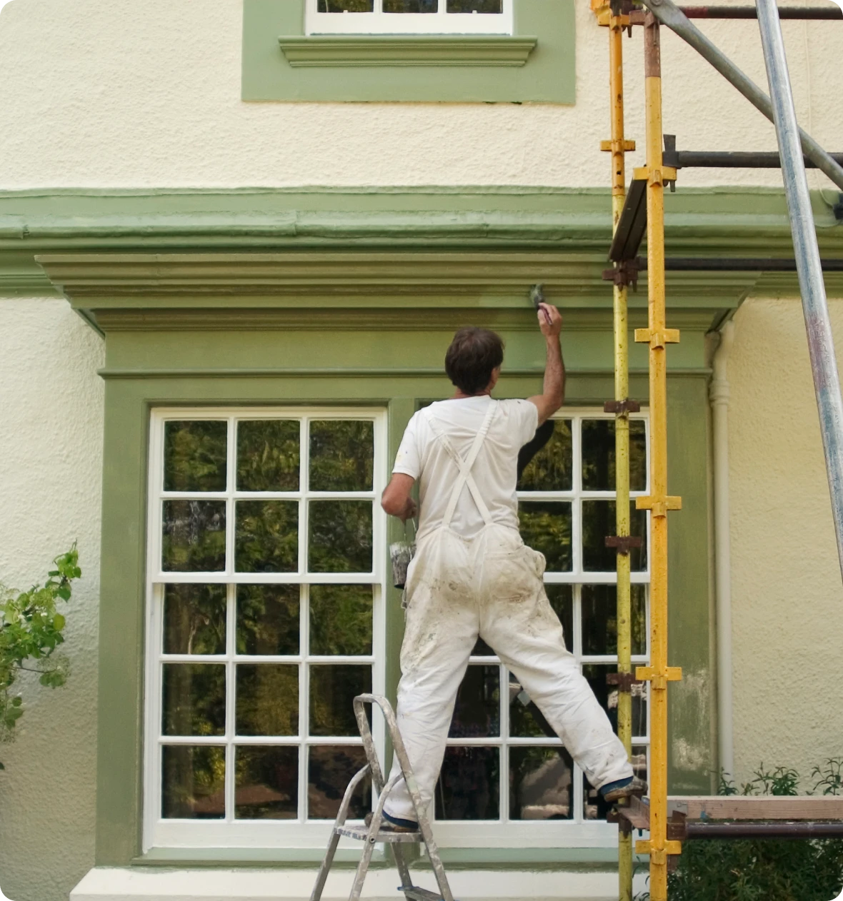 Man painting window trim on ladder