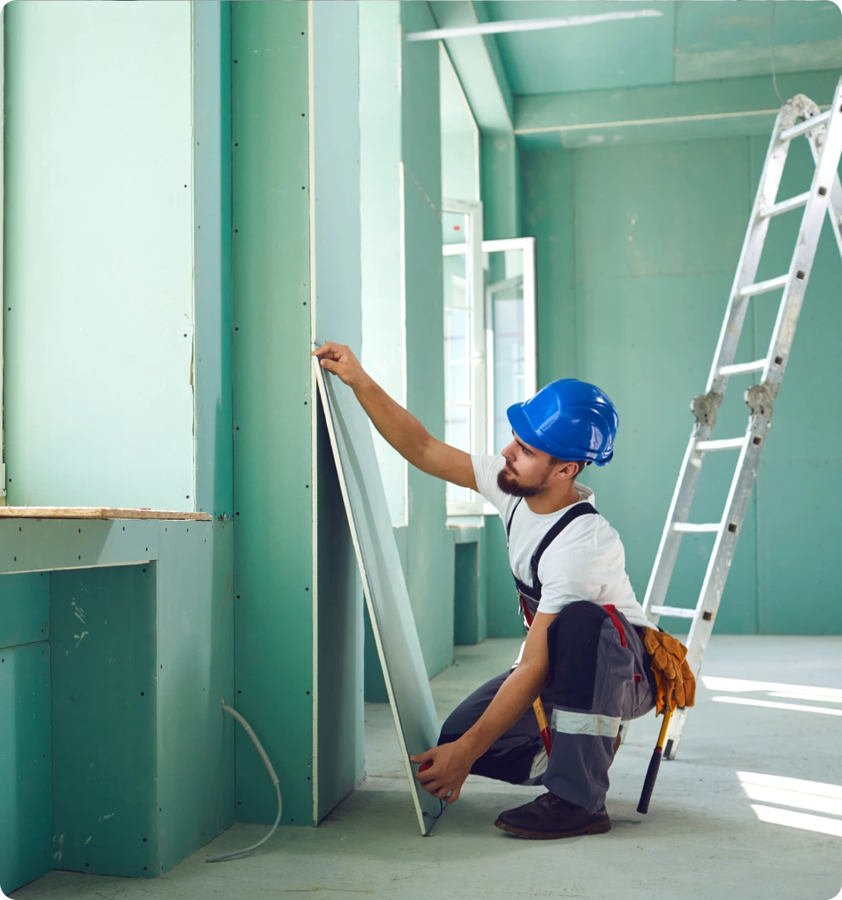 Construction worker installing drywall in room